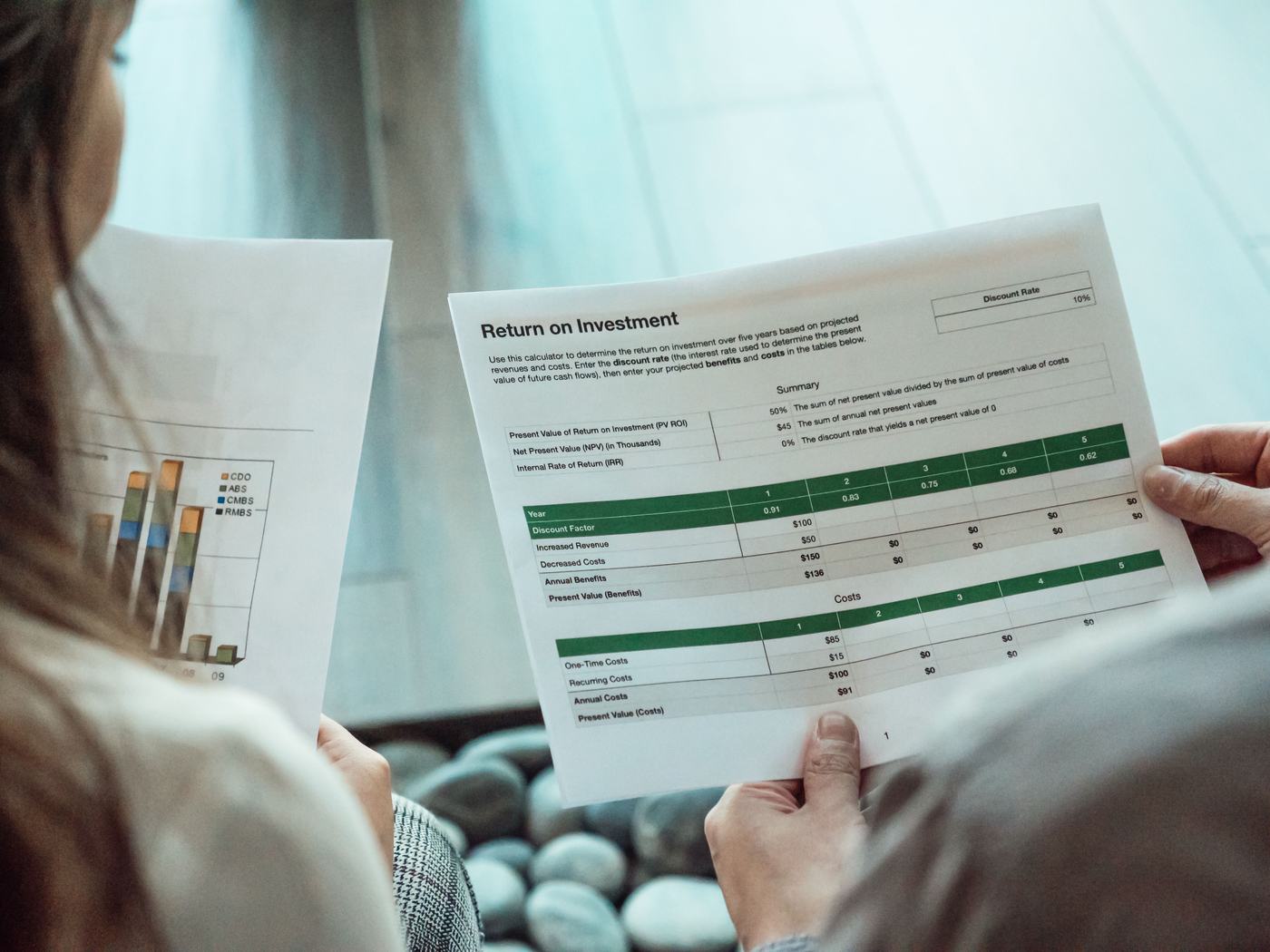 Person prüft eine Wirtschaftlichkeitsrechnung auf Papier.